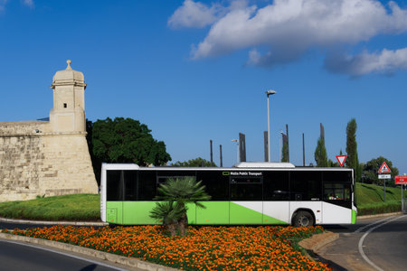 Valletta, Malta - September 11 2021: Public Transport Bus departing terminal. Green & white diesel coach driving away from Valletta central bus stop station next to the city walls, on a sunny day.のeditorial素材