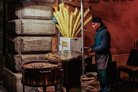 Rome, Italy - October 9 2021: Roasted chestnuts seller around Trevi Fountain. Night view of street vendor selling seasonal popped nuts food prepared over hot coals at Fontana di Trevi area.のeditorial素材