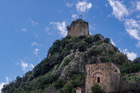 Karytaina 13th century castle with Greek flag on the hill. Low angle view of historic fortification remains against blue sky with clouds in Arcadia Peloponnese.のeditorial素材