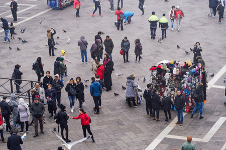 Venice Italy - February 22 2019: elevated day view of street vendor selling hats and carnival masks, with tourists on Saint Mark square, viewed from Saint Marks Basilica rooftop.のeditorial素材