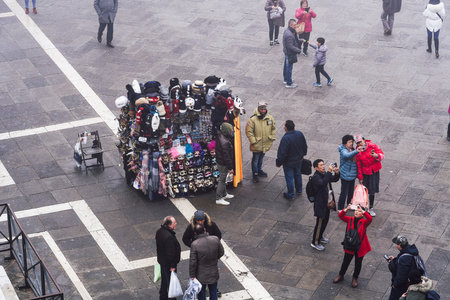 Venice Italy - February 22 2019: elevated day view of street vendor selling hats and carnival masks, with tourists on Saint Mark square, viewed from Saint Marks Basilica rooftop.のeditorial素材