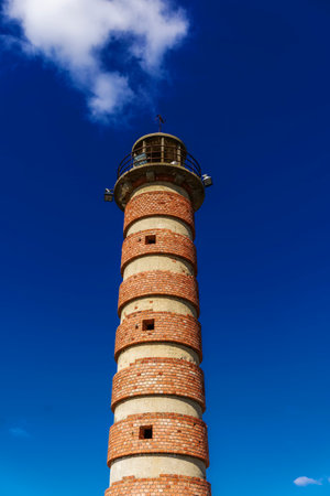 Lisbon Belem red brick waterfront lighthouse against blue sky, before Monument of the Discoveries, Padrao dos Descobrimentos.の写真素材
