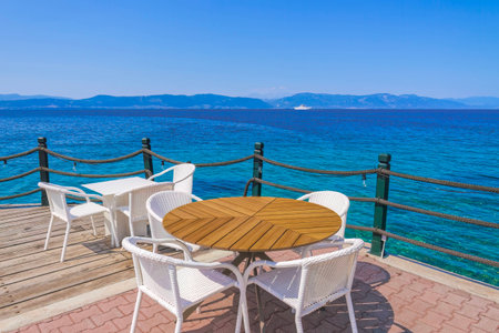 Empty cafe with chairs and tables by the seafront under a blue sky in summer.の写真素材