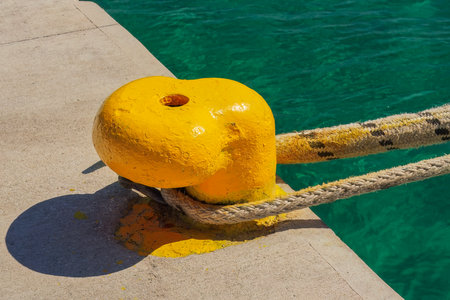 A thick hawser rope used to moor a ship on a yellow pier at the seaport.の写真素材