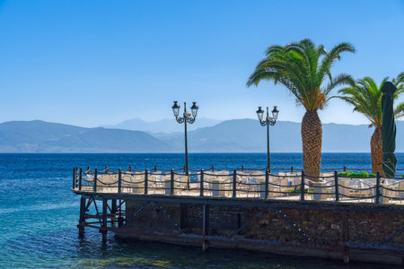 Empty cafe with chairs and tables by the seafront under a blue sky in summer.の写真素材