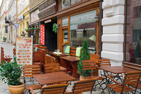 Bratislava, Slovakia - April 13 2019: Outdoor seating area with wooden chairs and tables with food menu chart display outside a Slovak restaurant.のeditorial素材