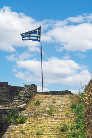 Greek flag waving on a must against sky with clouds on top of Agia Mavra Fort in Lefkada Ionian Island, Greece.の写真素材