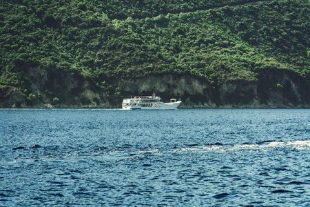 Small car and passengers ferry sailing next to a green plantation coastline in Lefkada Ionian Island Greece.の写真素材