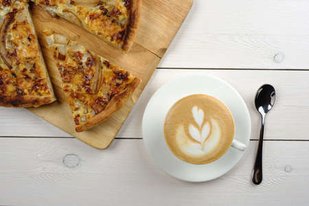 Tasty piece of cake with a cup of cappuccino and appliances on a white wooden table. Top viewの写真素材