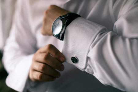 man in white shirt buttons on the hand cuffs to the clock