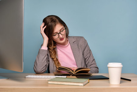 A girl in a pink sweatshirt and a gray jacket with a braid and glasses sits at a table , leaning on...