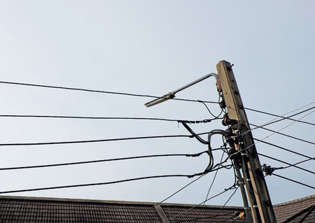 Lamp post with many cords among the light blue skyの写真素材