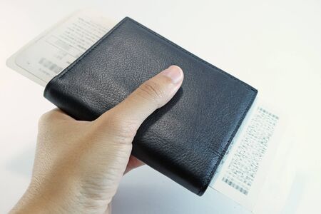 Flight Ticket inside passport are held by hand and hand ahead with white backgroundの写真素材