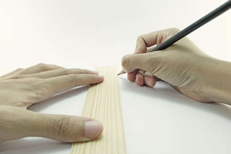drawing a line down on paper with a ruler and pencil with both handsの写真素材
