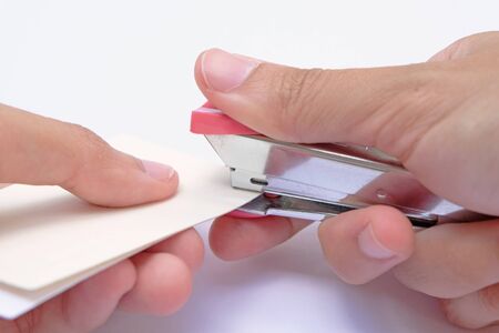 binding papers with stapler by both hands and white backgroundの写真素材