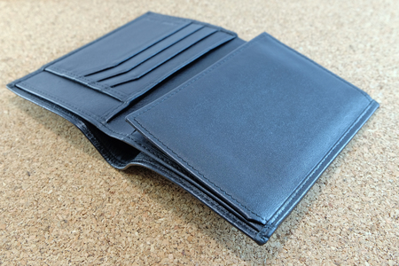 Black wallet is rolled out on plywood floorの写真素材