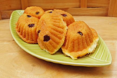 Several pieces of egg cake with raisin on green plate with wooden backgroundの写真素材