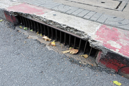 drain at edge of Footpath which is painted red and white color