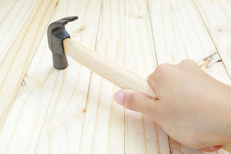 Hammering by tip of hammer with handle held by hand on wood floorの写真素材