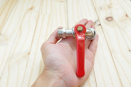 Top view of metal hole's faucet on palm on wood floorの写真素材