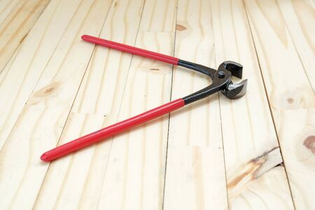 outstretched Mouth of eight inches pliers with red handle on wood floorの写真素材