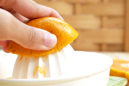The orange peel area (Selected focus) which is crushed by thumb on white hand juicer on wood backgroundの写真素材