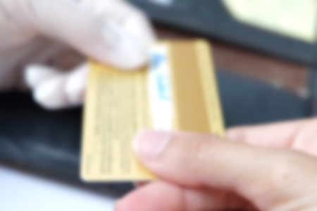 gold credit card is handed to another glove hand with black wallet on ground (blur mode)の写真素材