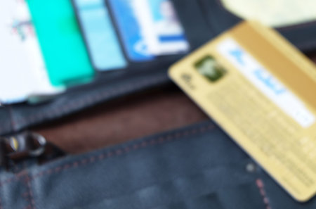 chip at back side of gold credit card shown signature on black wallet with other cards in blur mode