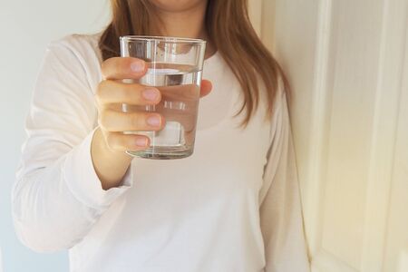 A woman holds a glass of drinking water for everyone. She wants to say that drinking water is beneficial to the body. Good health conceptの写真素材