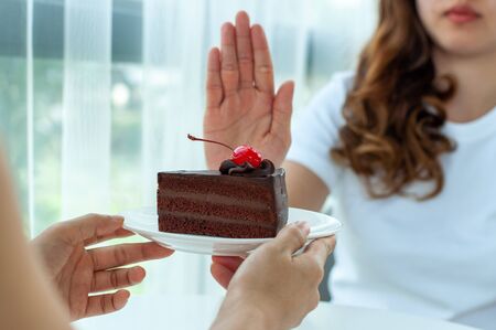 Healthy women push the plate into chocolate cake. Refusing to eat foods that contain trans fats and carbohydrates for good shape. diet conceptの写真素材