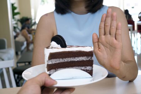 One of the health-care girls used a hand to push a plate of chocolate cake. Refuse to eat foods that contain Trans Fat.の写真素材