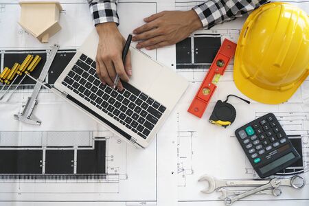 Engineers work with laptops and blueprints. Calculate and check the construction project.の写真素材
