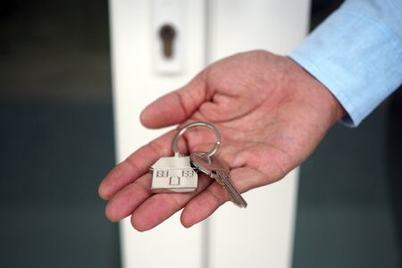 The hand of the banker holds the house key. Home and land mortgage conceptの写真素材
