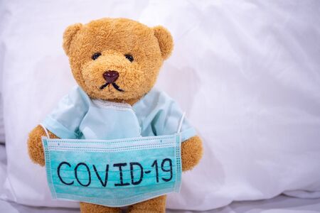 Sick teddy bear with mask writes Covid-19. The situation of the 2019-nCoV virus infection in Wuhan is spreading around the world. Deadly plague of the world. concept wear mask to protect coronavirusの写真素材