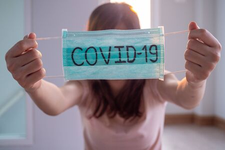woman with mask writes Covid-19. The situation of the 2019-nCoV virus infection is spreading around the world. Deadly plague of the world. The concept wear a mask to protect coronavirusの写真素材