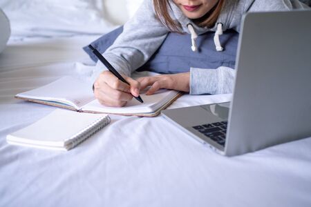 Businesswoman wearing pajamas working at home in the bedroom due to the spread of the virus Covid-19. Stay home, stop the spread of the virus. stay safe, working from home and Social distance.の写真素材