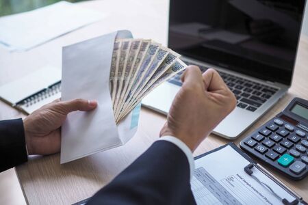 Happy young asian employee business man holding money bonus card in paper envelope to increasing of salary or promotion new position in office, bonusの写真素材