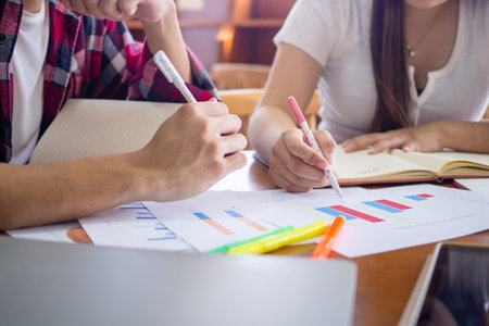 Students or college students studying and reading sitting and doing homework together in the...