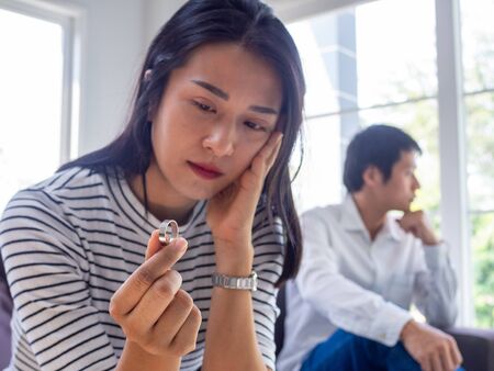 Asian woman sat with the wedding ring, thinking seriously sad and sad after arguing with her husband. The problems of lovers must separate. Family issues, divorce, washing, causing lossの写真素材