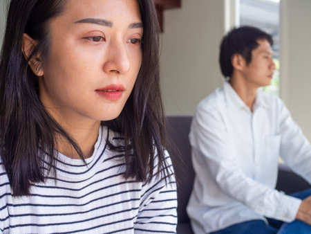 Asian couple is sad and anxious not speak after quarrel. The upset wife feels angry, thinking of...
