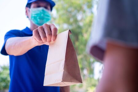 One woman ordered food online to eat at home. The person  orders products or food online, receives parcels from delivery man That put a mask on the door of the house.の写真素材