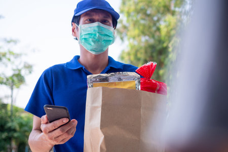 The delivery man wears a mask to prevent the spread of germs and send the goods or food that the...