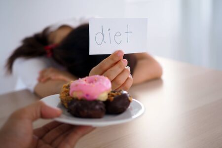 A woman holding a sign that says that Diet is for the person who sends the dish to the donut.の写真素材