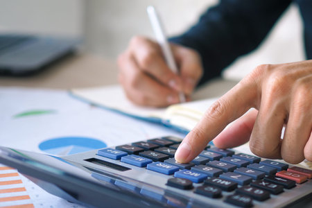 Businessman working on desk office with using a calculator to calculate the numbers, finance...