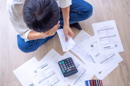 Asian man are stressed about financial problems. With invoices and various bills and calculators...