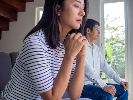 Depressed young wife feels resentful and sad. After an argument with a stubborn husband sitting on the sofa unhappy young wives bored with bad relationships, bored with marriage problemsの写真素材