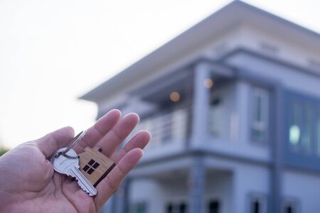 The owner holds a new home key from a real estate dealer. House for sale and for rent concept.の写真素材