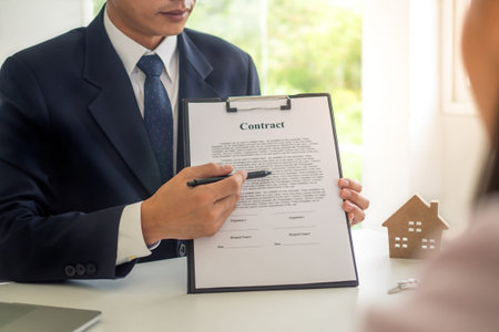 The house sales representative is showing the details of the contract or house purchase documents to...