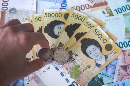 The hand that is placing coins on the bank notes in Korean currencyの写真素材