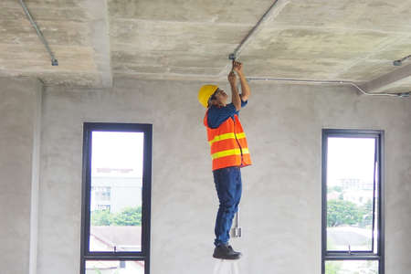 Electrician working in the room Maintenance technicians install wiring in the home.の写真素材